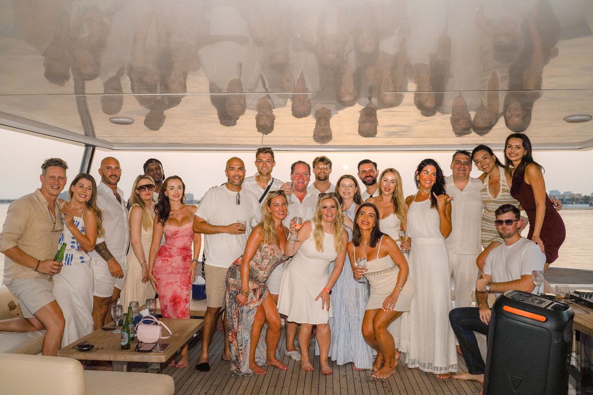 Forty guests posing together on the aft deck of a private yacht at sunset