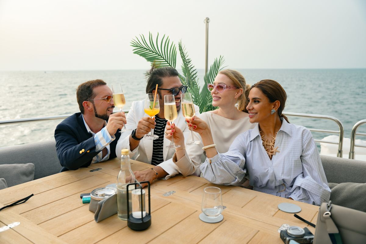 Guests raising Champagne glasses on the aft deck of a superyacht off Dubai