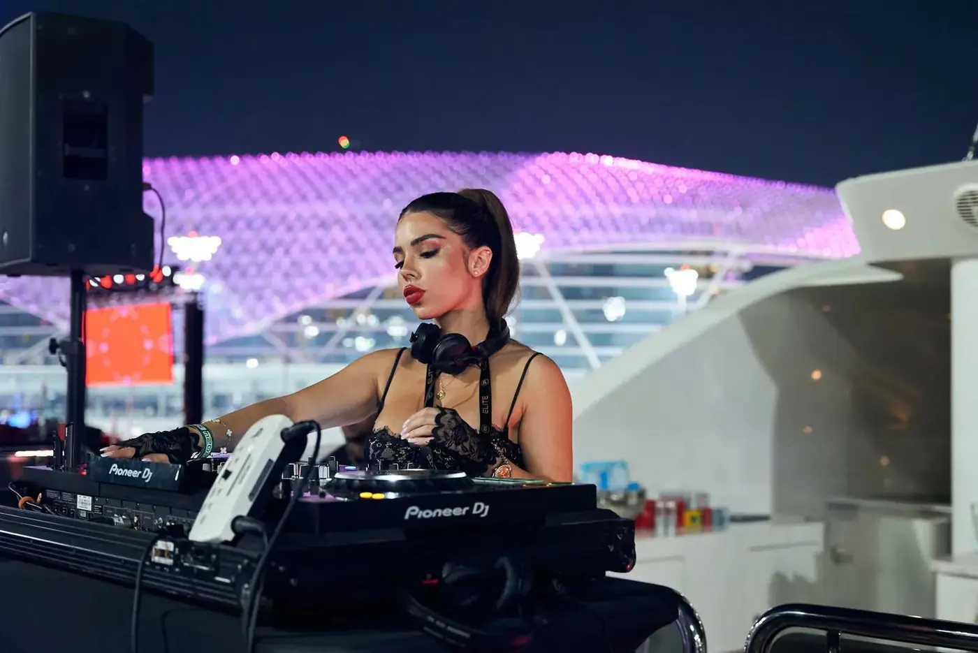 A DJ on the deck of a superyacht in Yas Marina at night during the Grand Prix
