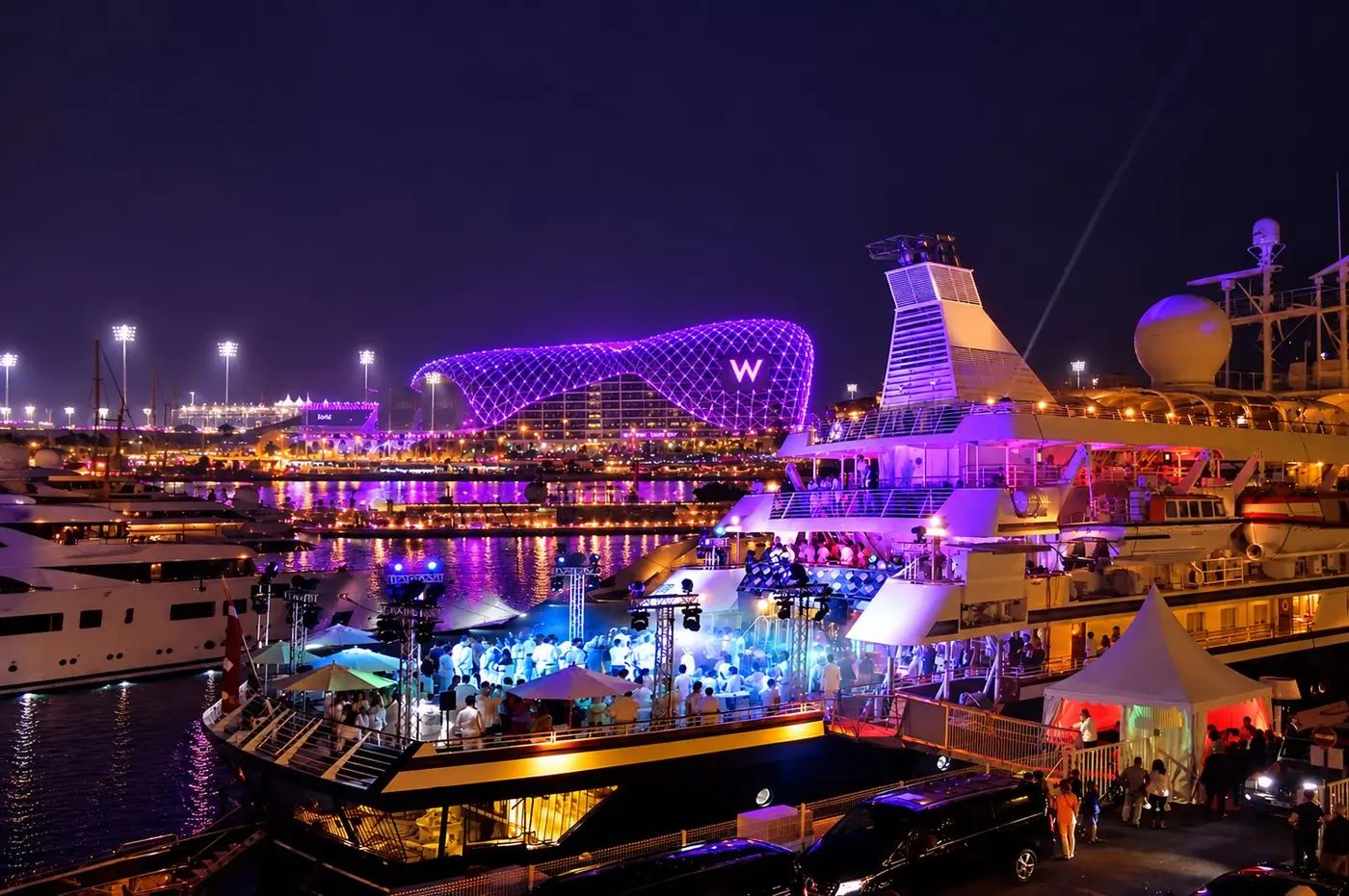 Yas Marina at night during the Abu Dhabi Grand Prix weekend, superyachts lit up by the track