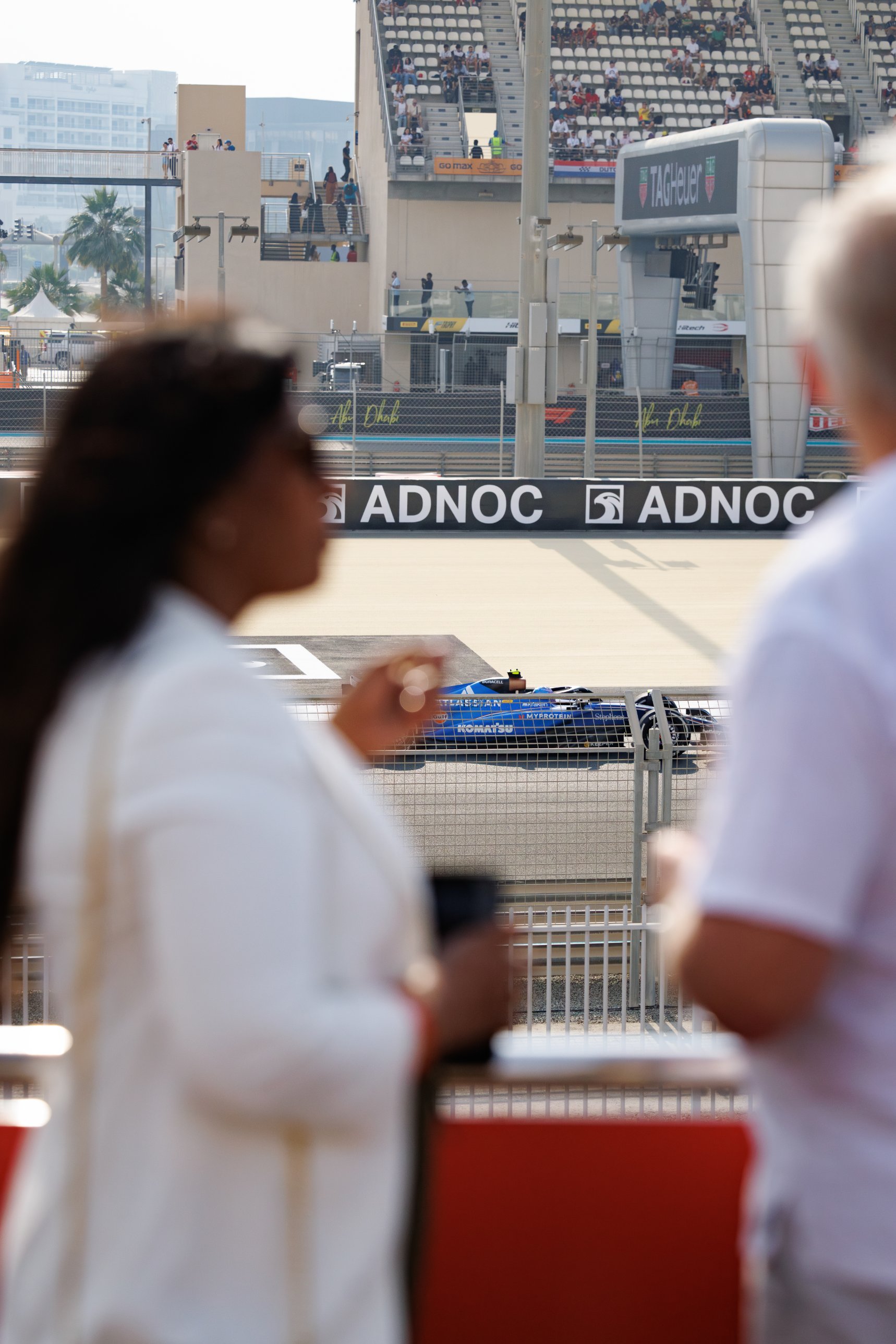Guests on a private yacht watching a Formula 1 car pass on the Yas Marina Circuit