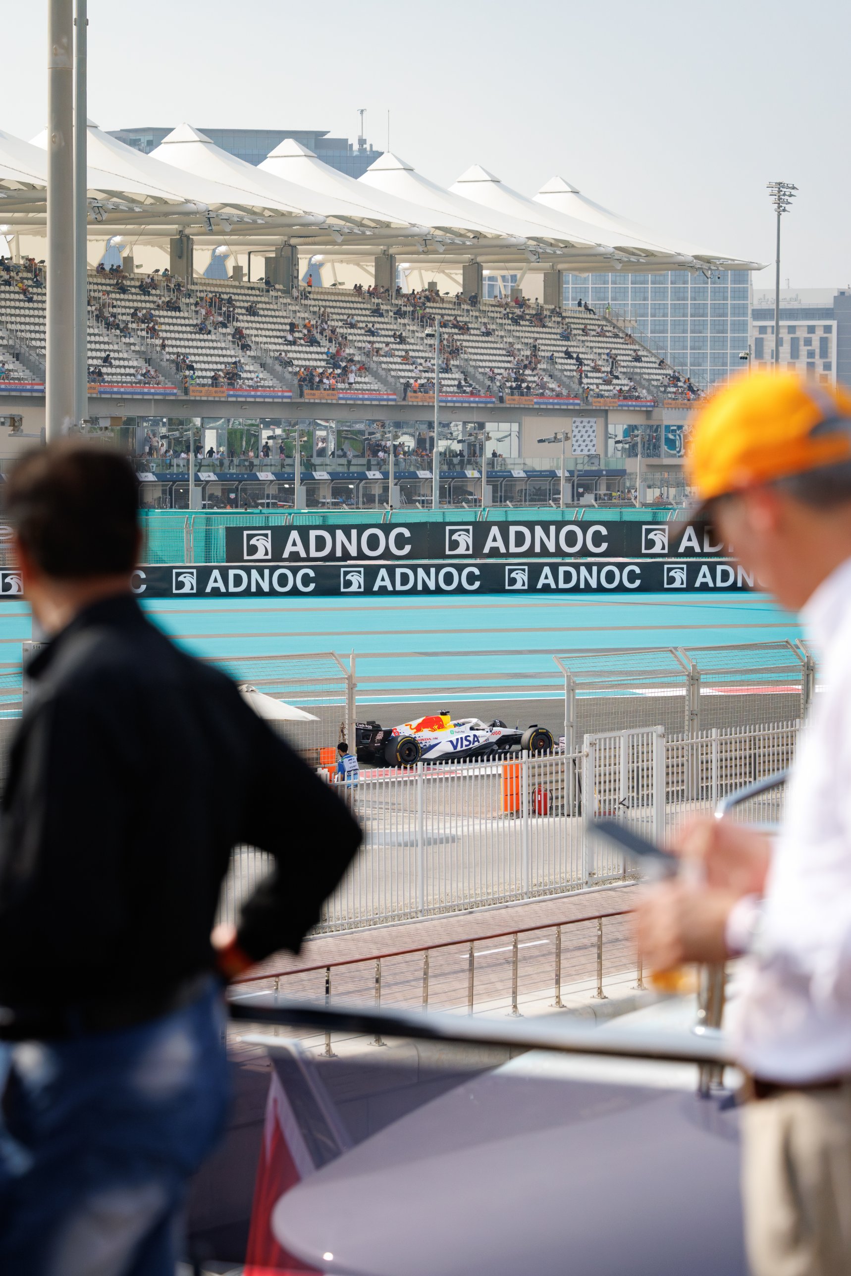 Guests on the megayacht deck watching a Formula 1 car on the Yas Marina Circuit