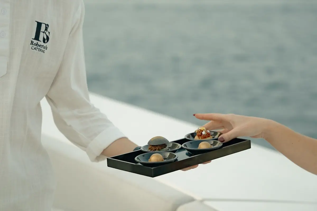 Waiter serving canapés to guests on a yacht deck