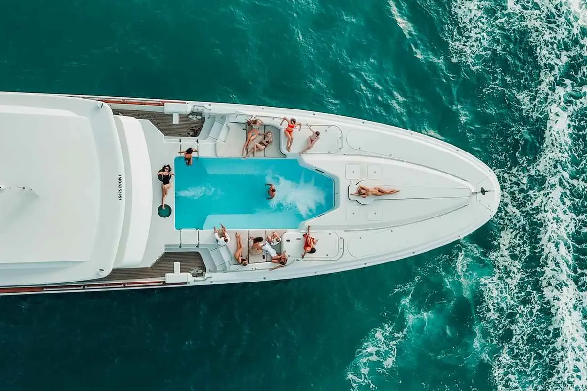 Aerial view of a yacht with a deck pool cruising off Dubai