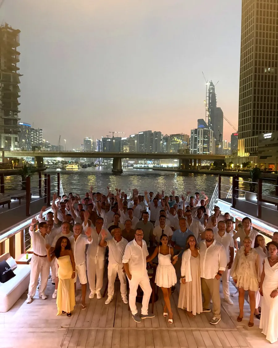 Guests dressed in white on the deck of a private boat in Dubai at dusk