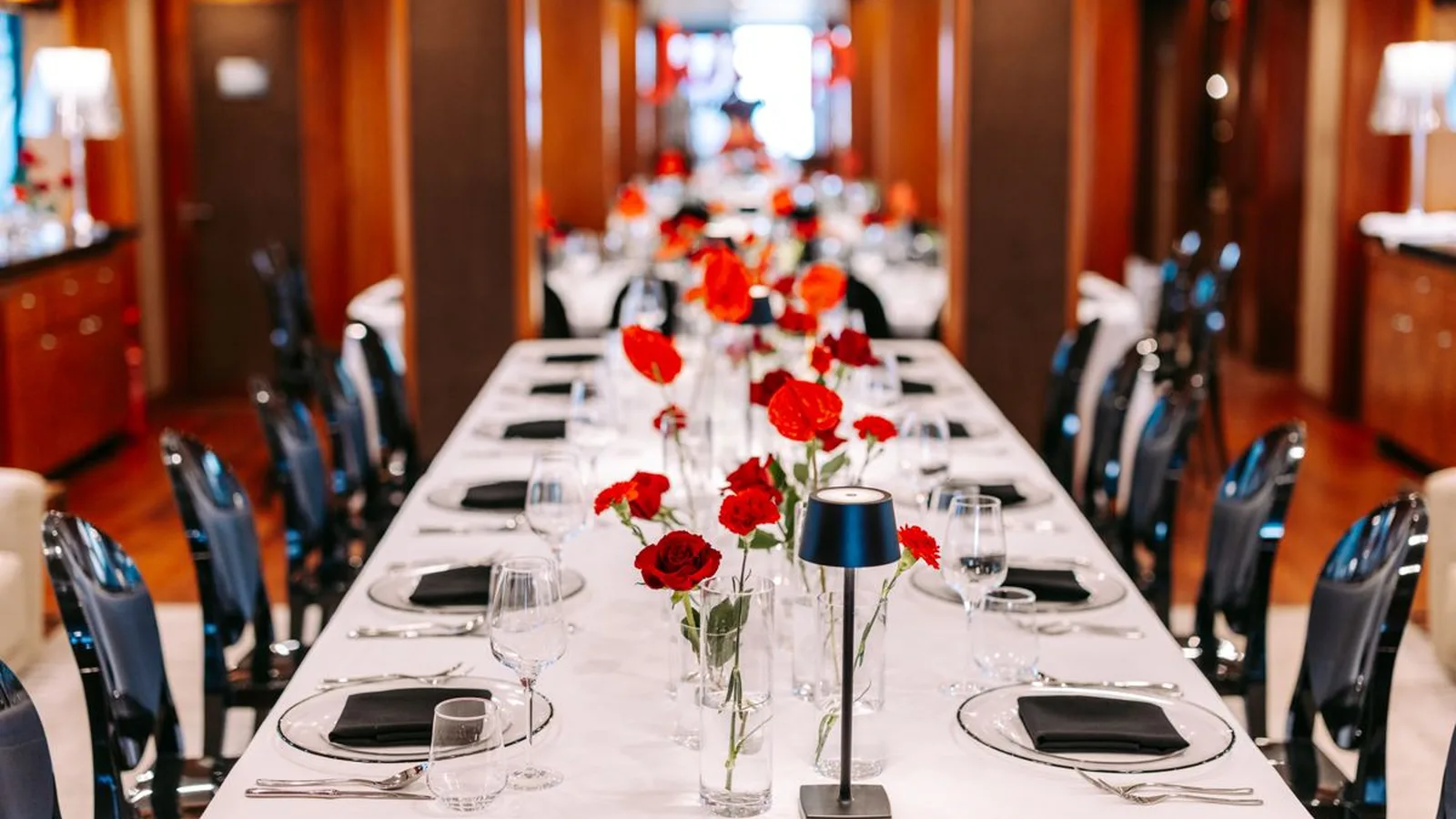 A long table set for a seated dinner in the saloon of a superyacht in Dubai