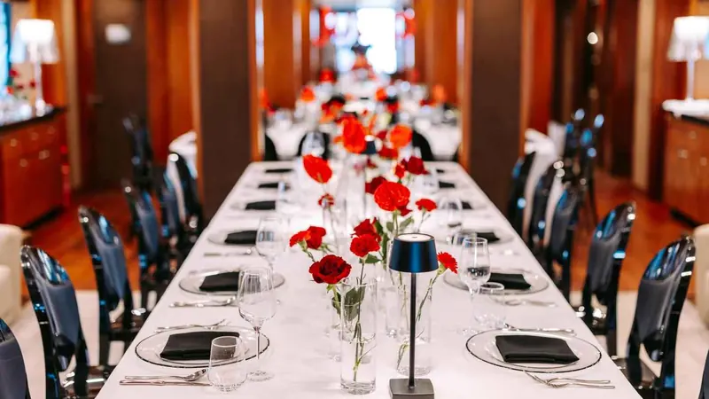 Long dinner table with red roses in the salon of a superyacht in Dubai