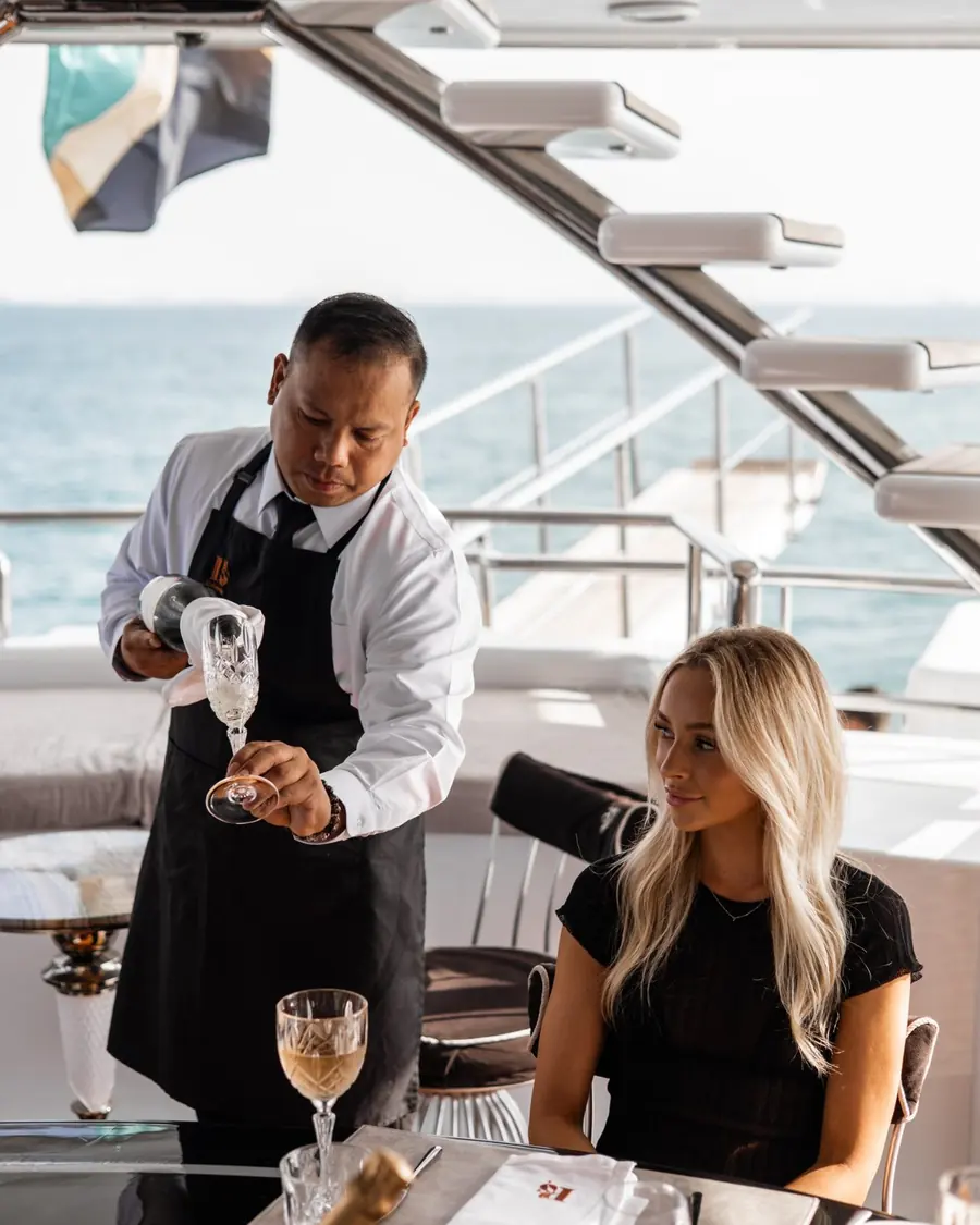 Crew member serving lunch on the deck of a yacht