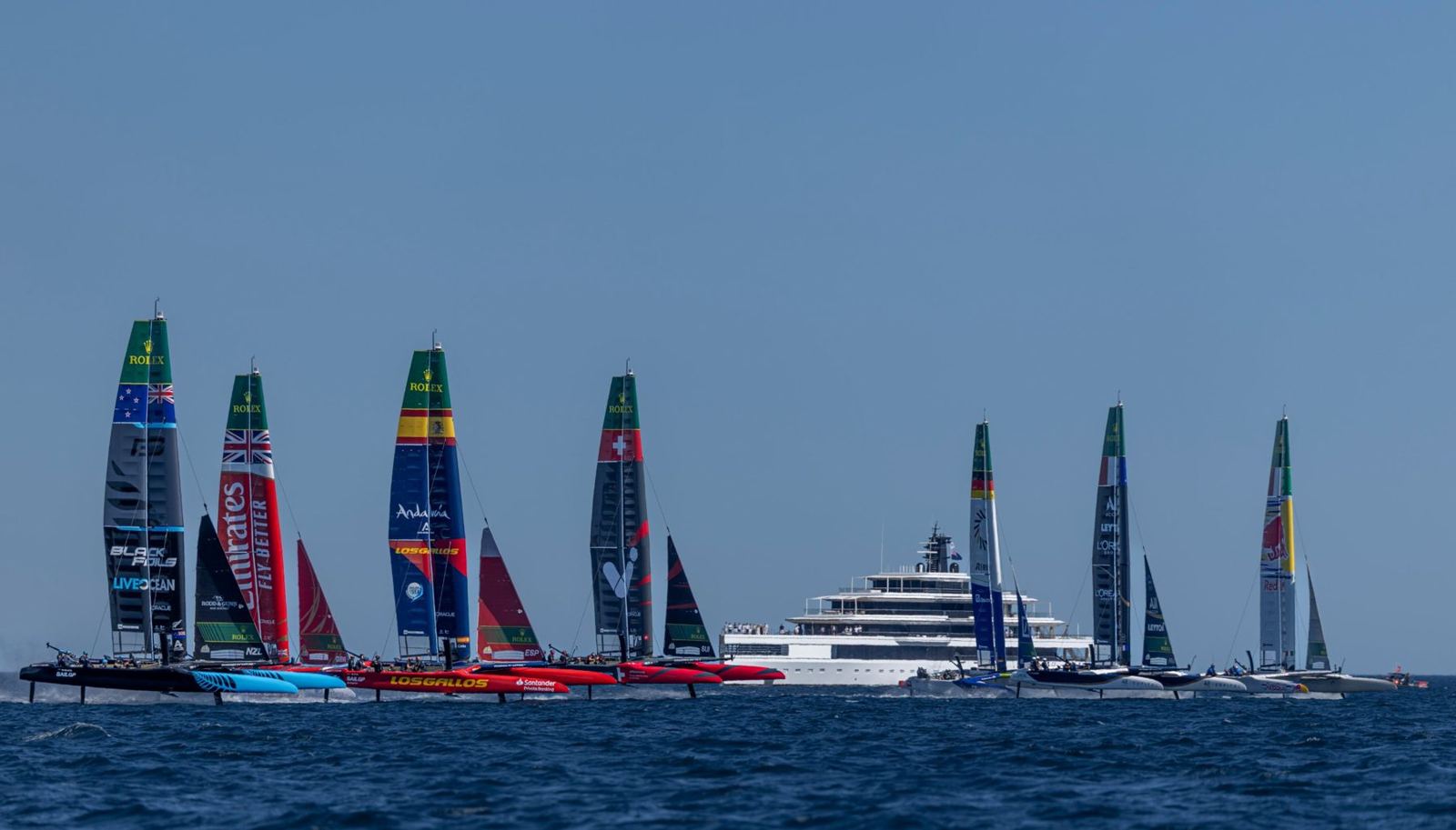 SailGP F50 catamarans racing past spectator yachts in Dubai