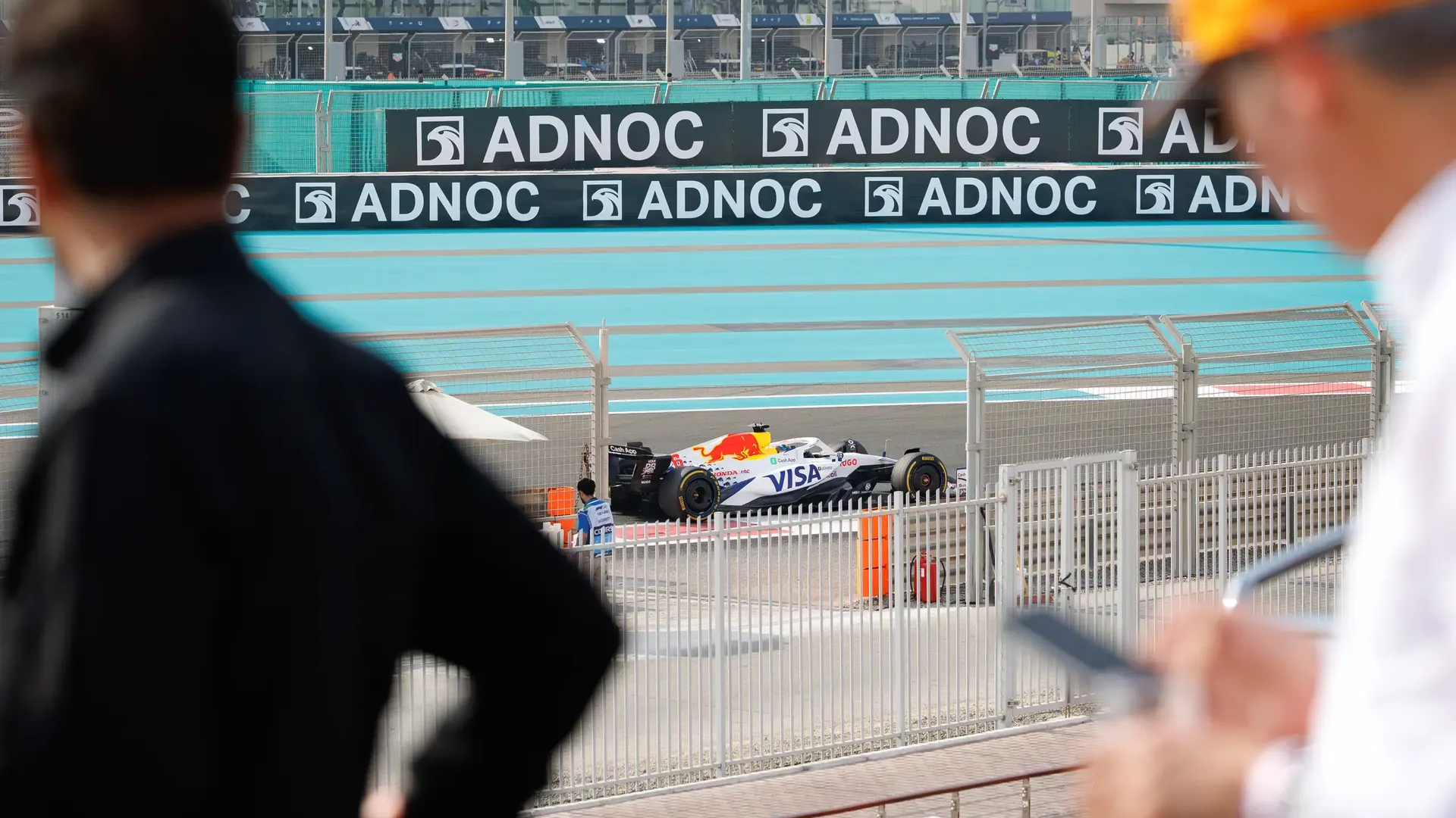 An F1 car racing past guests watching from a yacht at Yas Marina