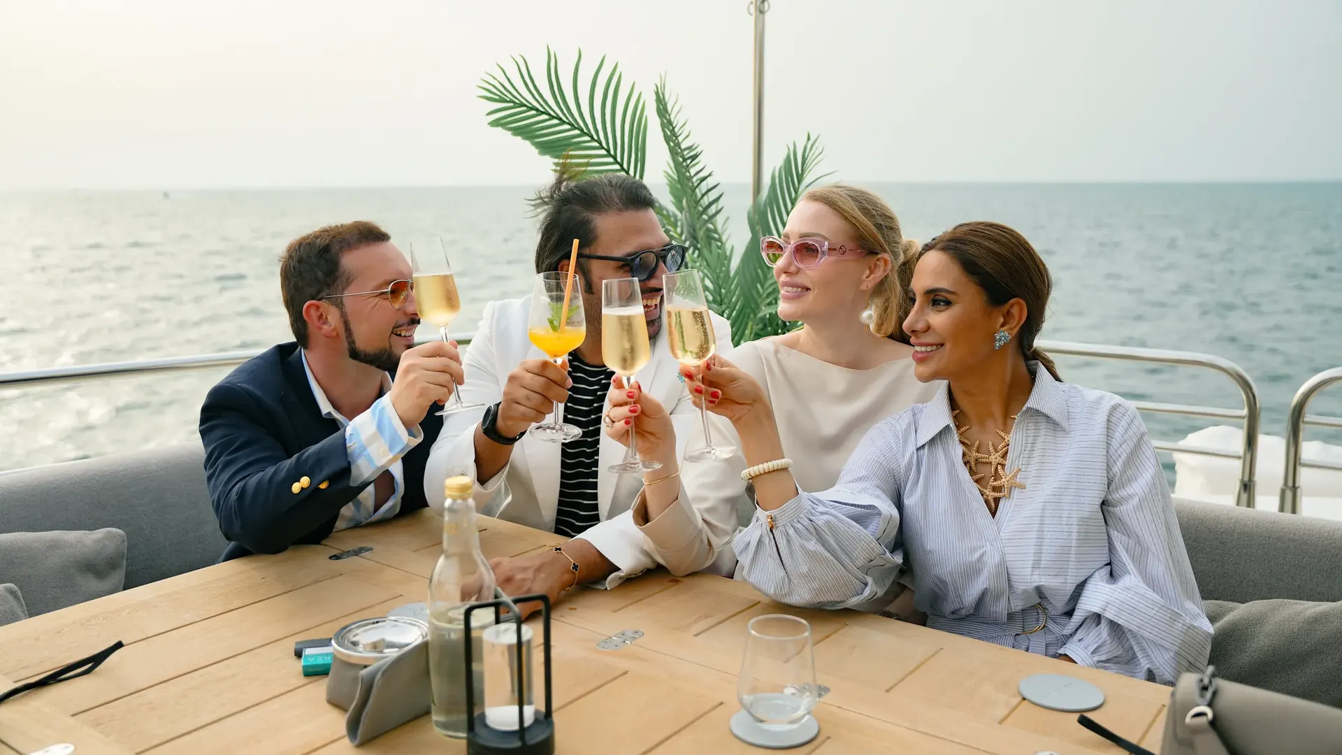 Guests toasting around a table on a yacht at sea